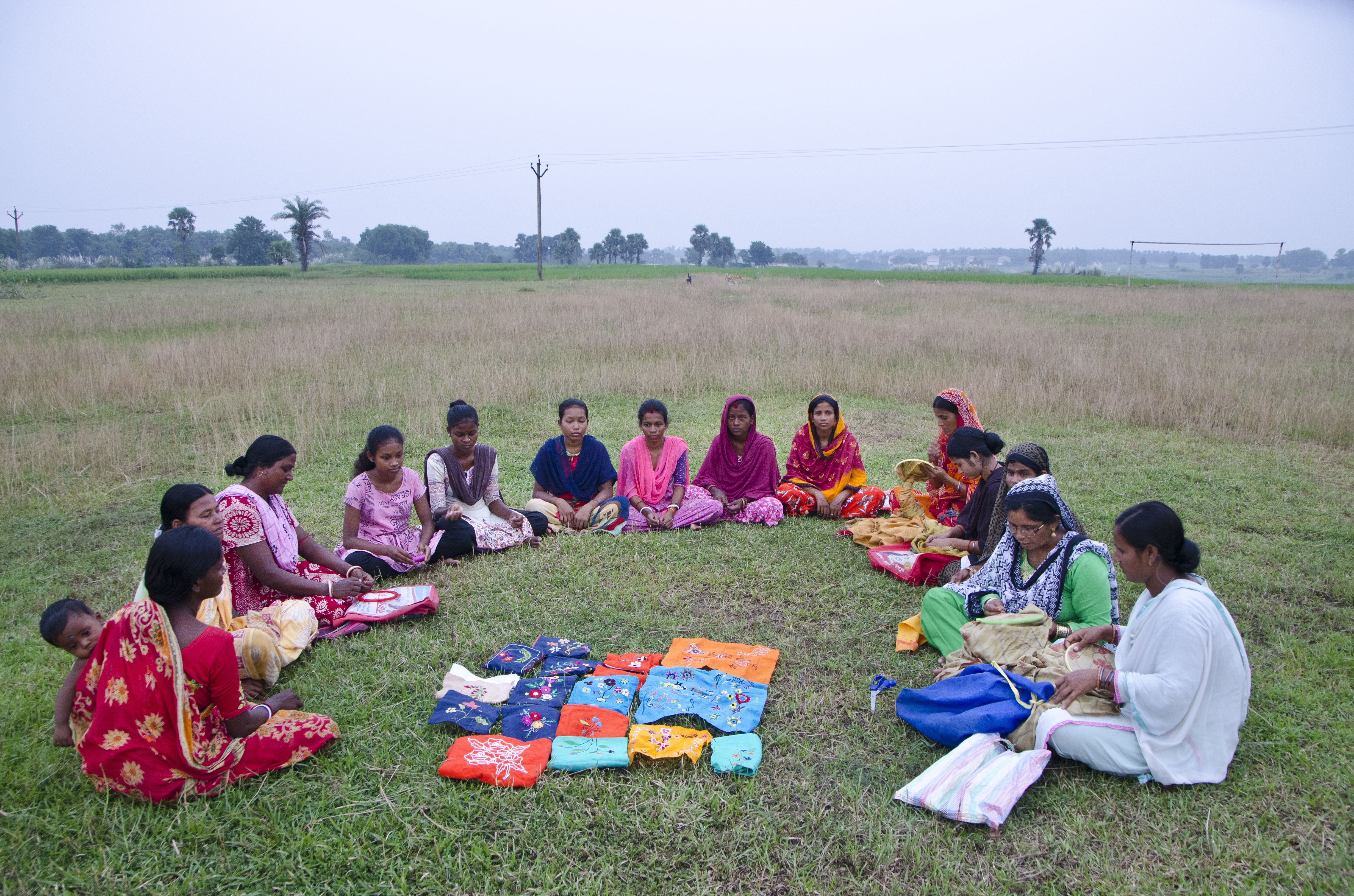 Kvinder sidder i halvcirkel og væver